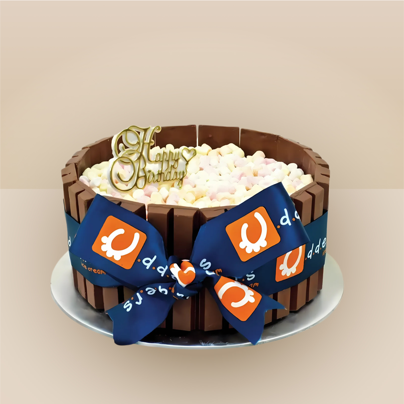 Udders ice cream birthday cake wrapped in chocolate wafer bars and filled with mini marshmallows, decorated with a branded navy ribbon bow and gold Happy Birthday topper