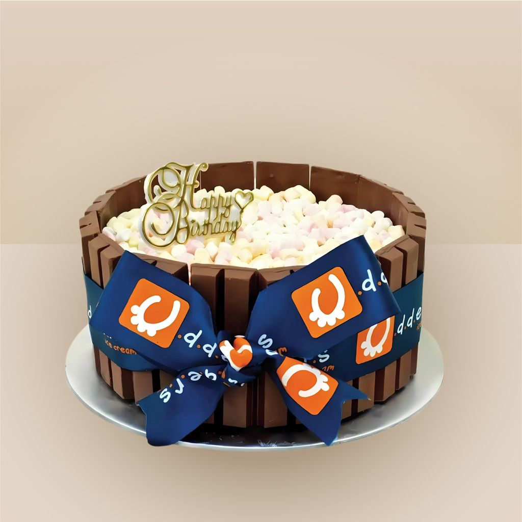 Udders ice cream birthday cake wrapped in chocolate wafer bars and filled with mini marshmallows, decorated with a branded navy ribbon bow and gold Happy Birthday topper