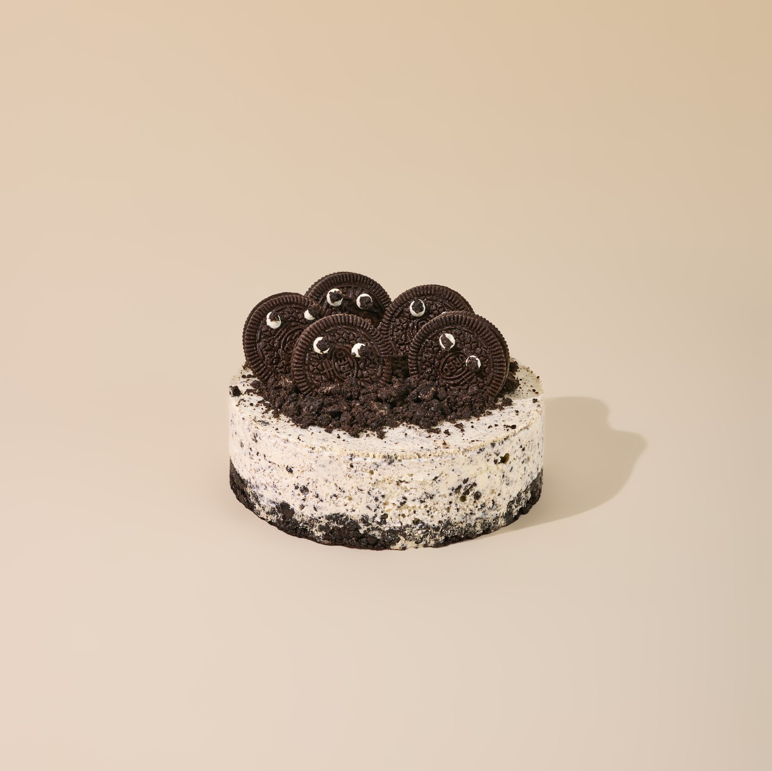 Cookies and cream ice cream cake studded with chocolate cookie crumbs, topped with whole chocolate sandwich cookies on an Oreo crust