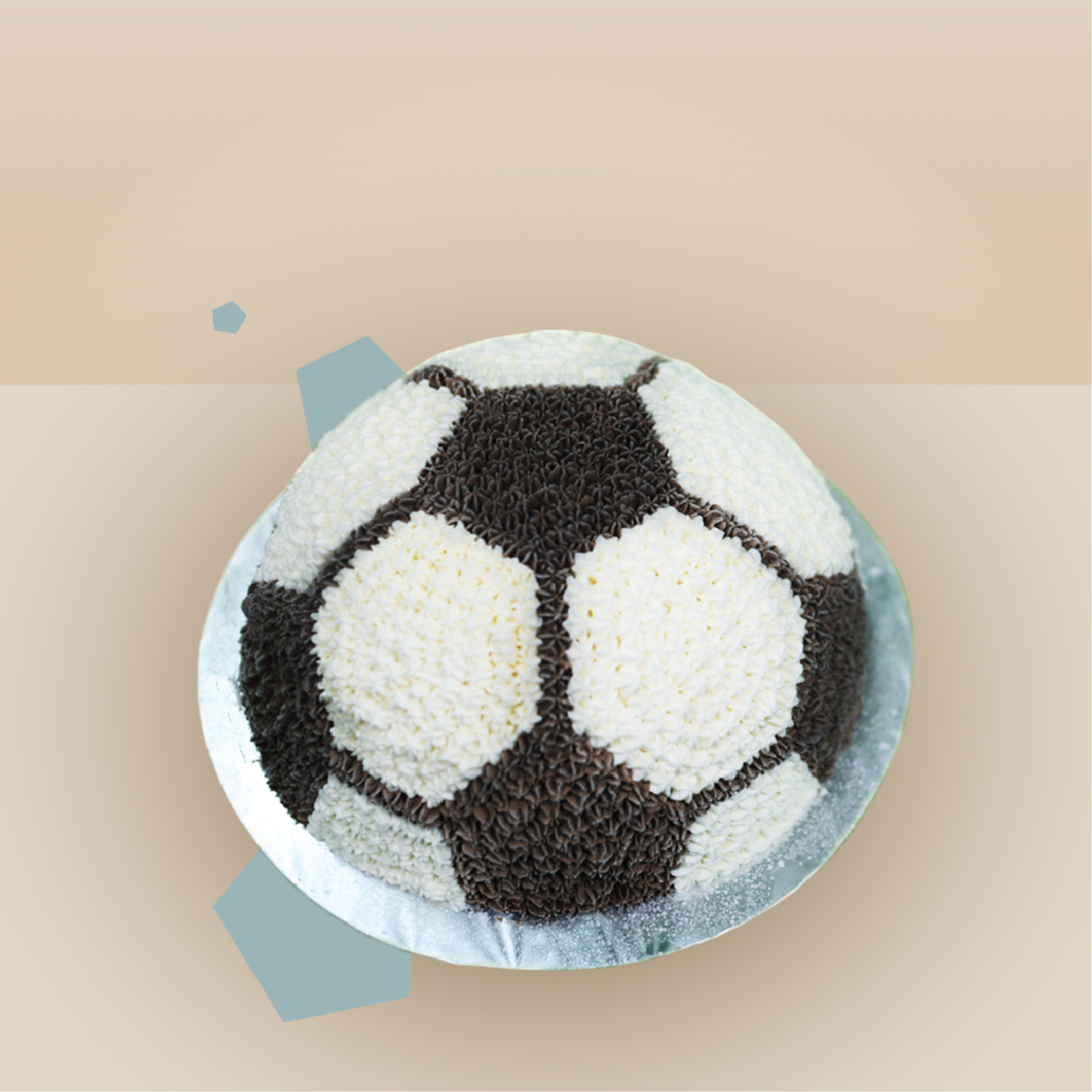 Dome-shaped football ice cream cake decorated with black and white piped cream rosettes in a soccer ball pattern