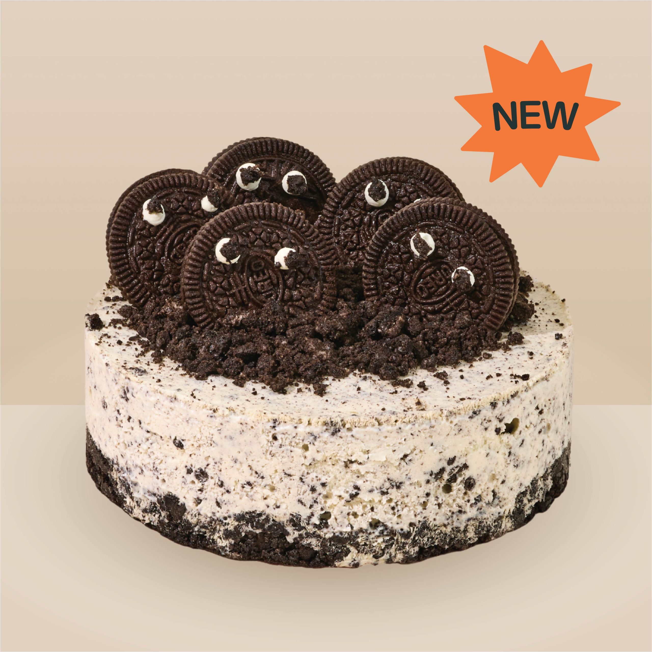 Cookies and cream ice cream cake studded with chocolate cookie crumbs, topped with whole chocolate sandwich cookies on an Oreo crust